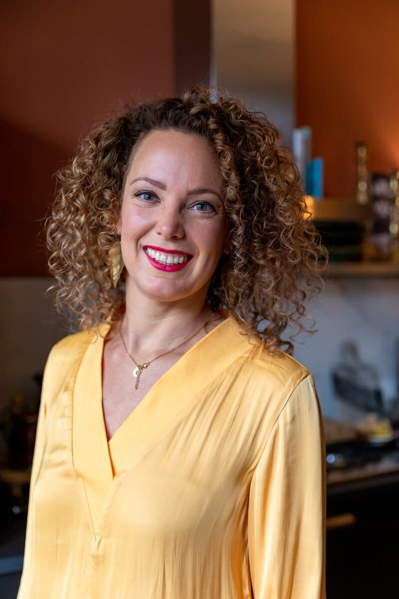 Portret van Anne-Marieke Visser in gele blouse, warm glimlachend.
